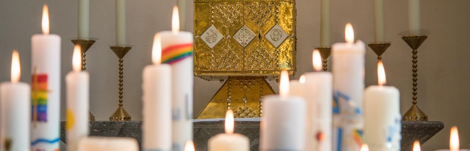 27.04.2019 Feier der Erstkommunion in St. Pankratius in Köln-Worringen - Brennende Kommunionkerzen vor dem Tabernakel in der Kirche St. Pankratius in Köln-Worringen.